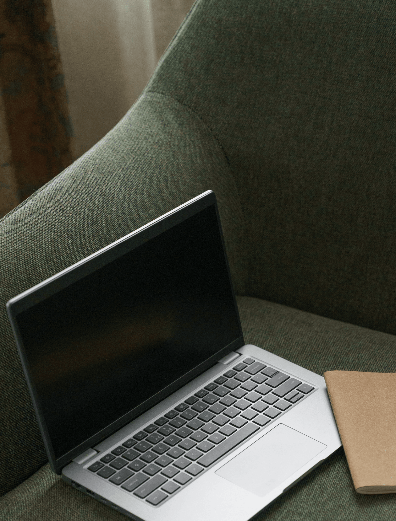 laptop and notebook on a green chair