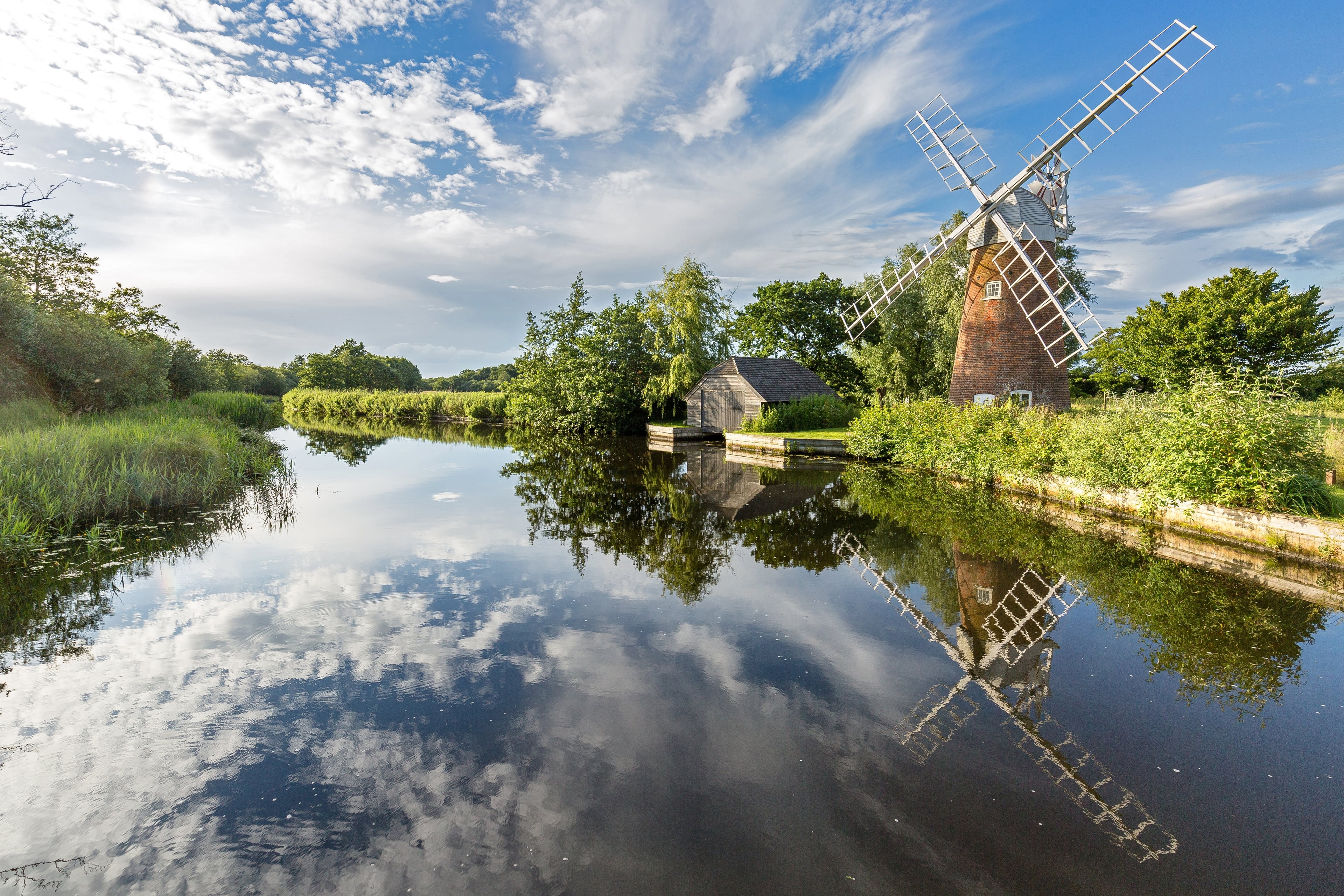sunny norfolk broads with open water pathway and windmill