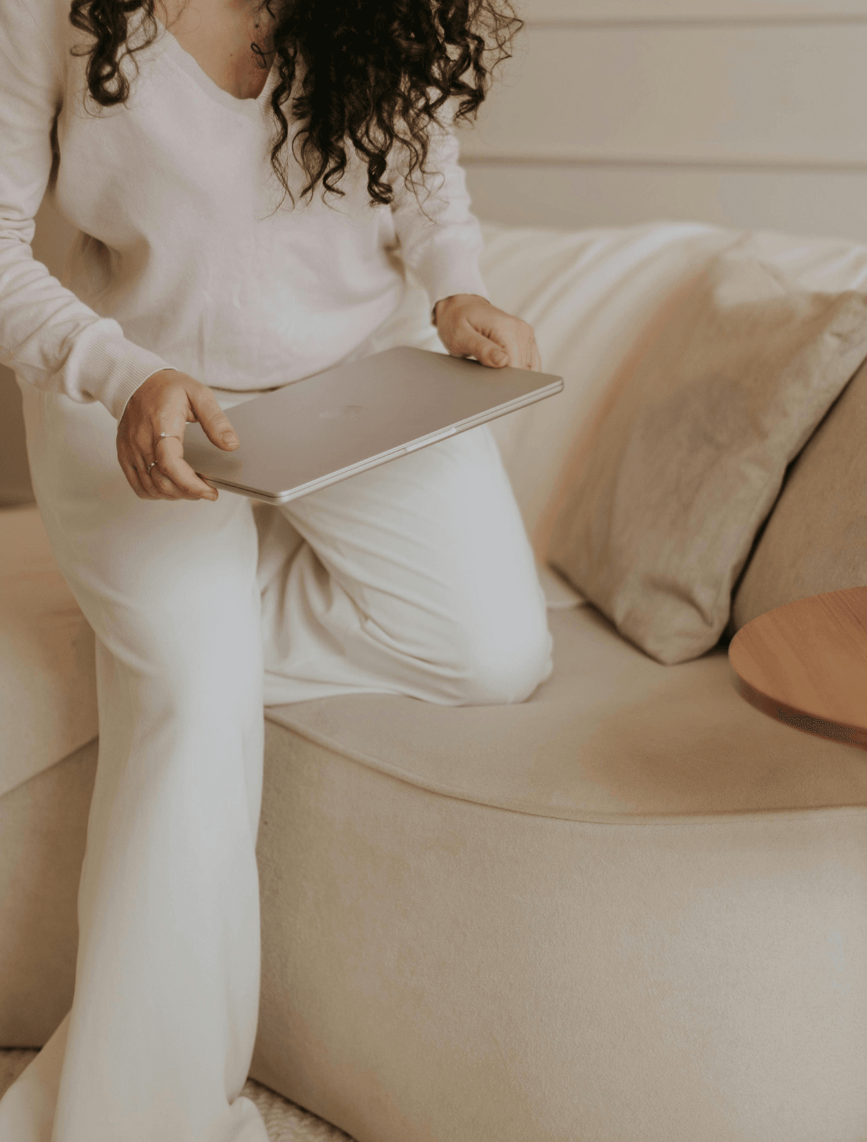 someone sitting down on a sofa with their laptop