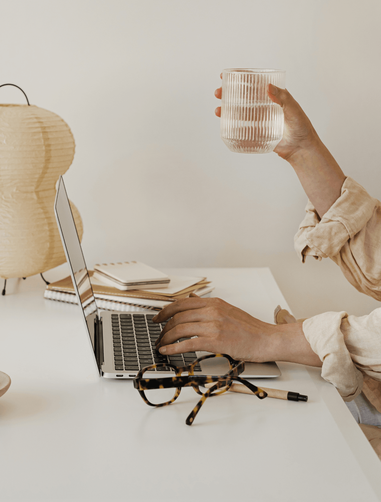 someone working on their laptop holding a glass of water