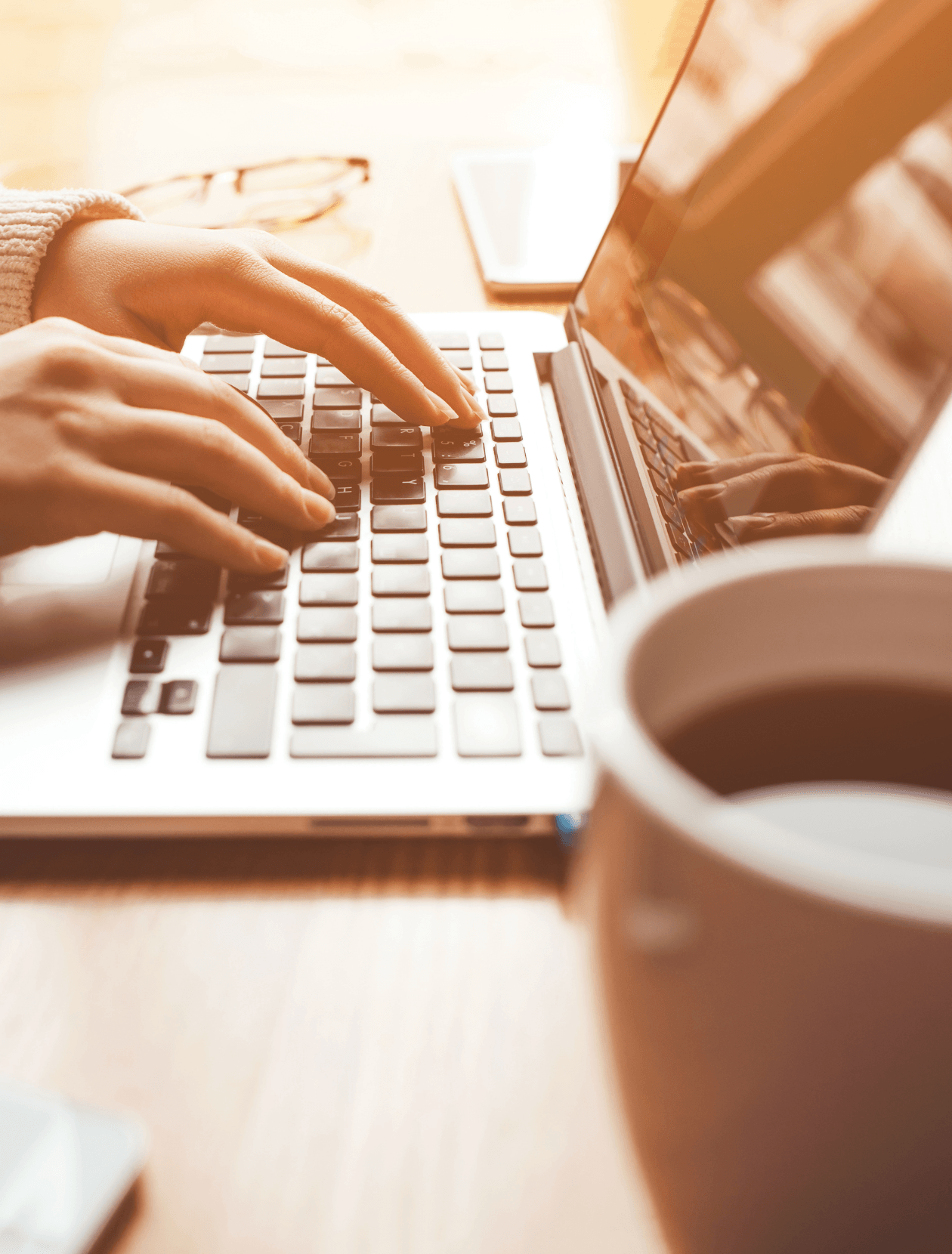 someone typing on a laptop next to a cup of coffee
