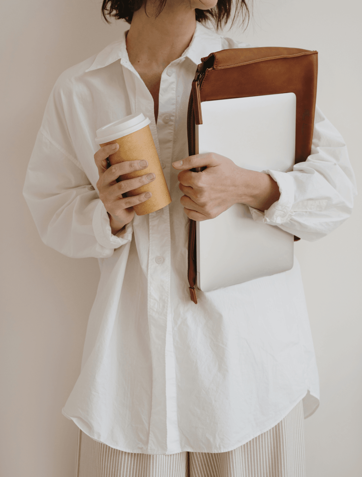 someone holding laptop with takeaway coffee cup