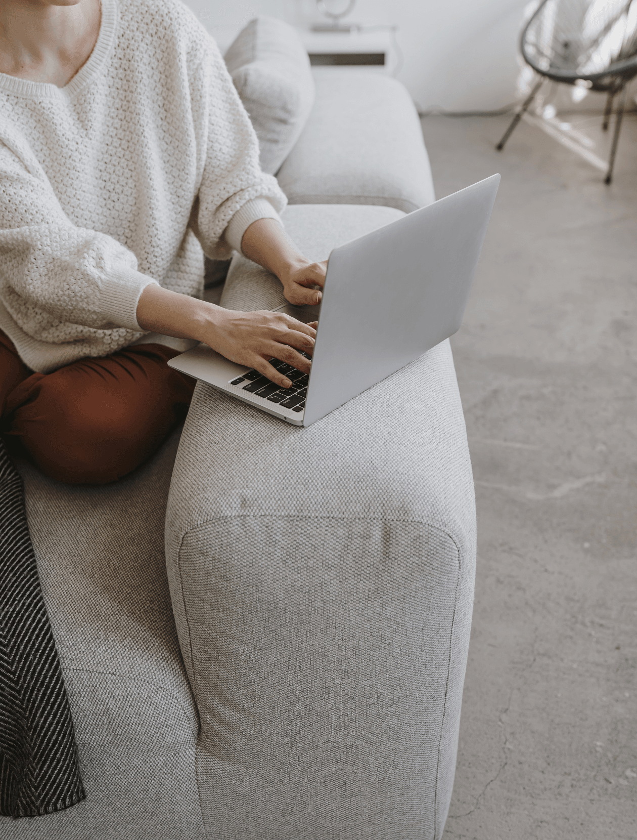 someone sitting on the sofa with their laptop